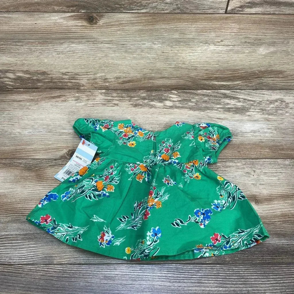 Flat lay of Cat & Jack newborn green floral dress showing gathered waist and ruffle sleeves on wood background