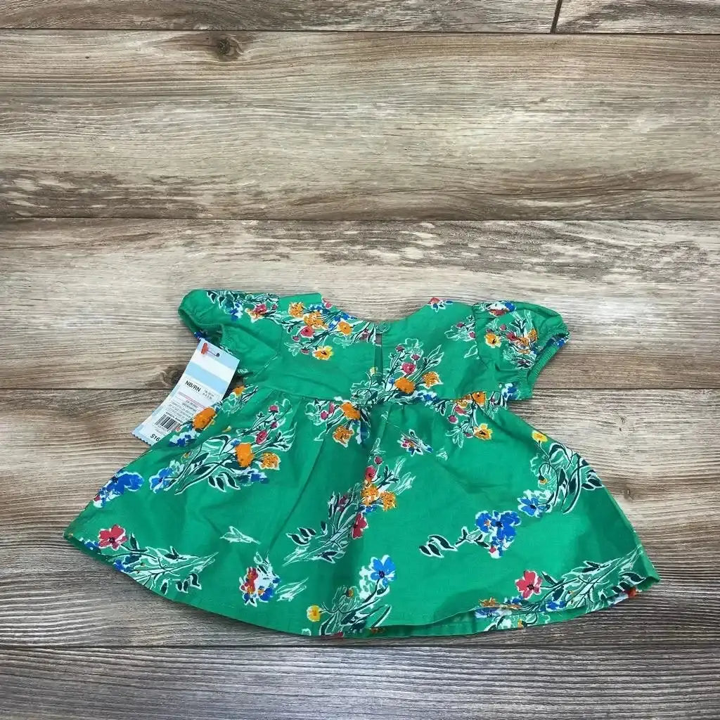 Flat lay of Cat & Jack newborn green floral dress showing gathered waist and ruffle sleeves on wood background