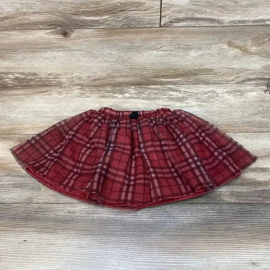 Flat lay of red plaid toddler skirt size 2T showing elastic waistband and layered tulle overlay on light wood floor