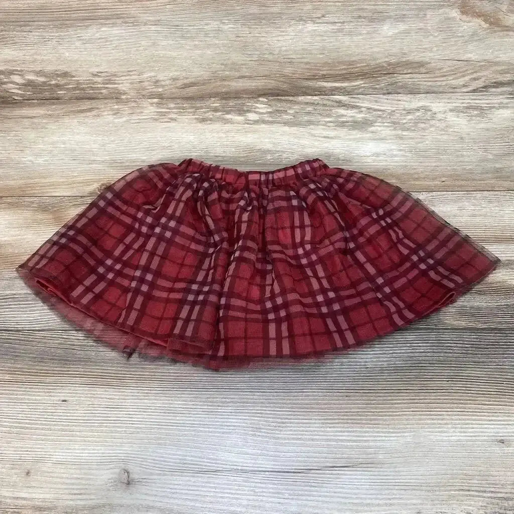 Flat lay of Disney plaid skirt sz 2T showcasing red tartan print with elastic waist and tulle trim on wood plank floor