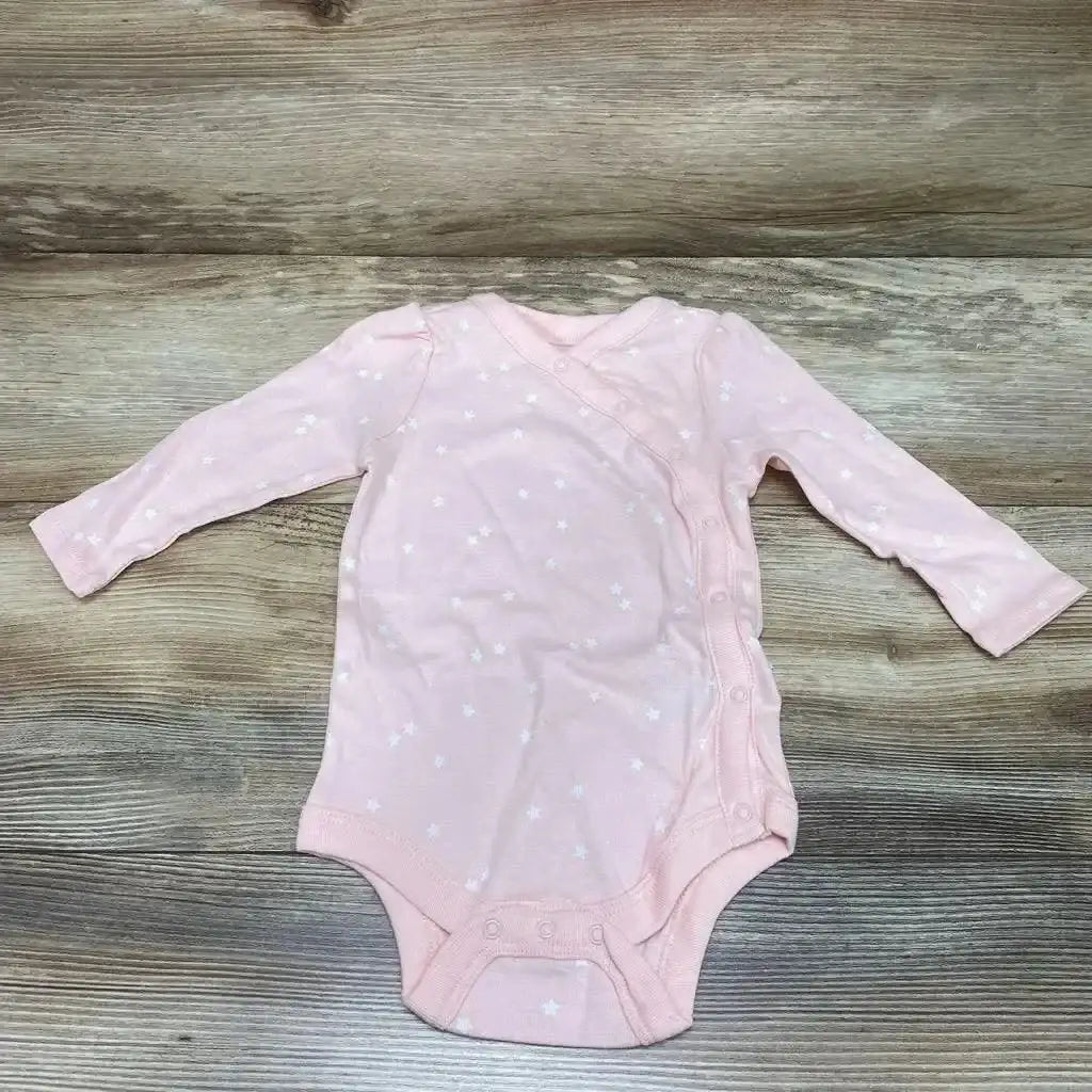 Flat-lay pink BabyGap kimono-style long-sleeve bodysuit with white star print and side snap closures on wood background