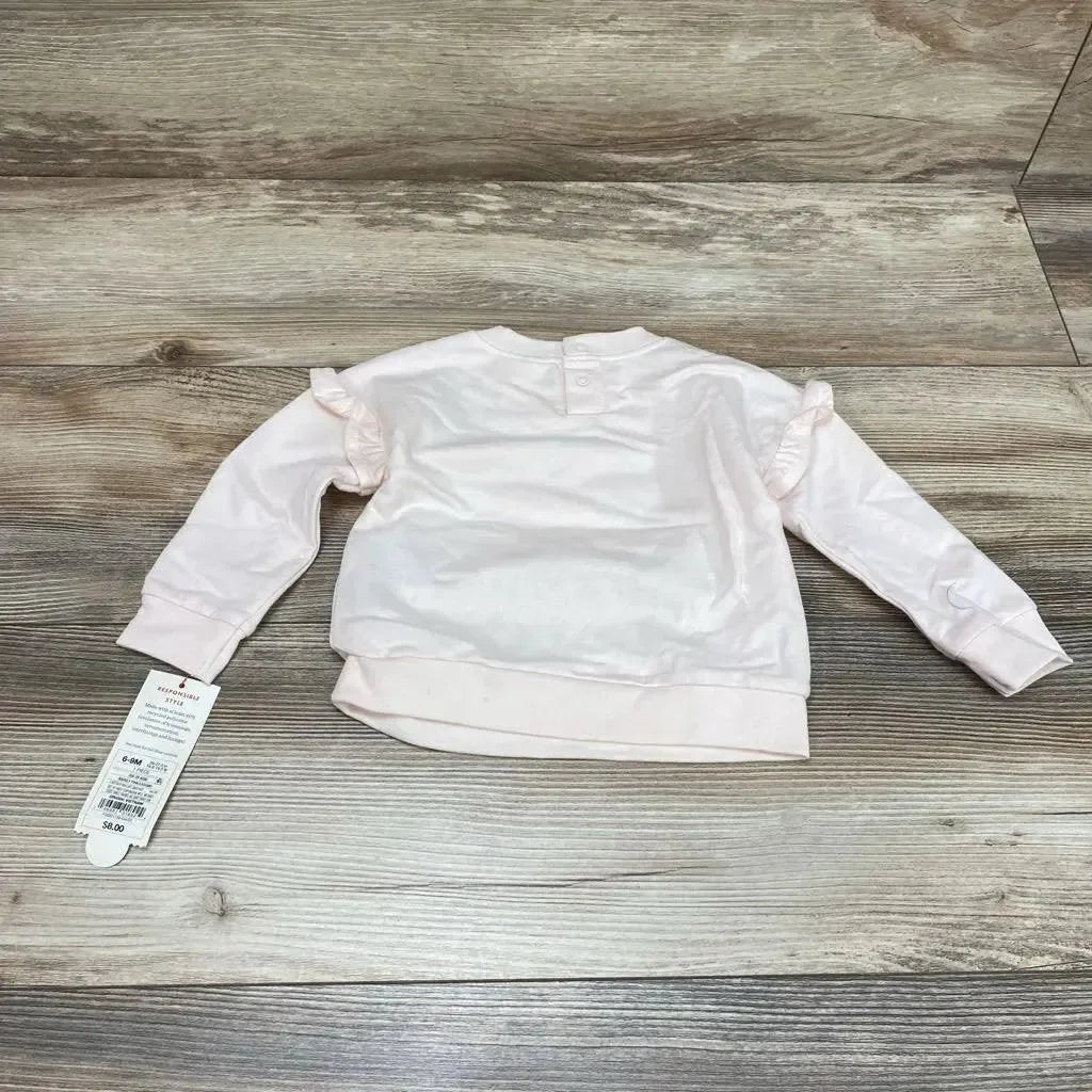 Back view of Cat & Jack pink baby sweatshirt (6–9 months) showcasing ruffle shoulder details and back snap on wood floor background