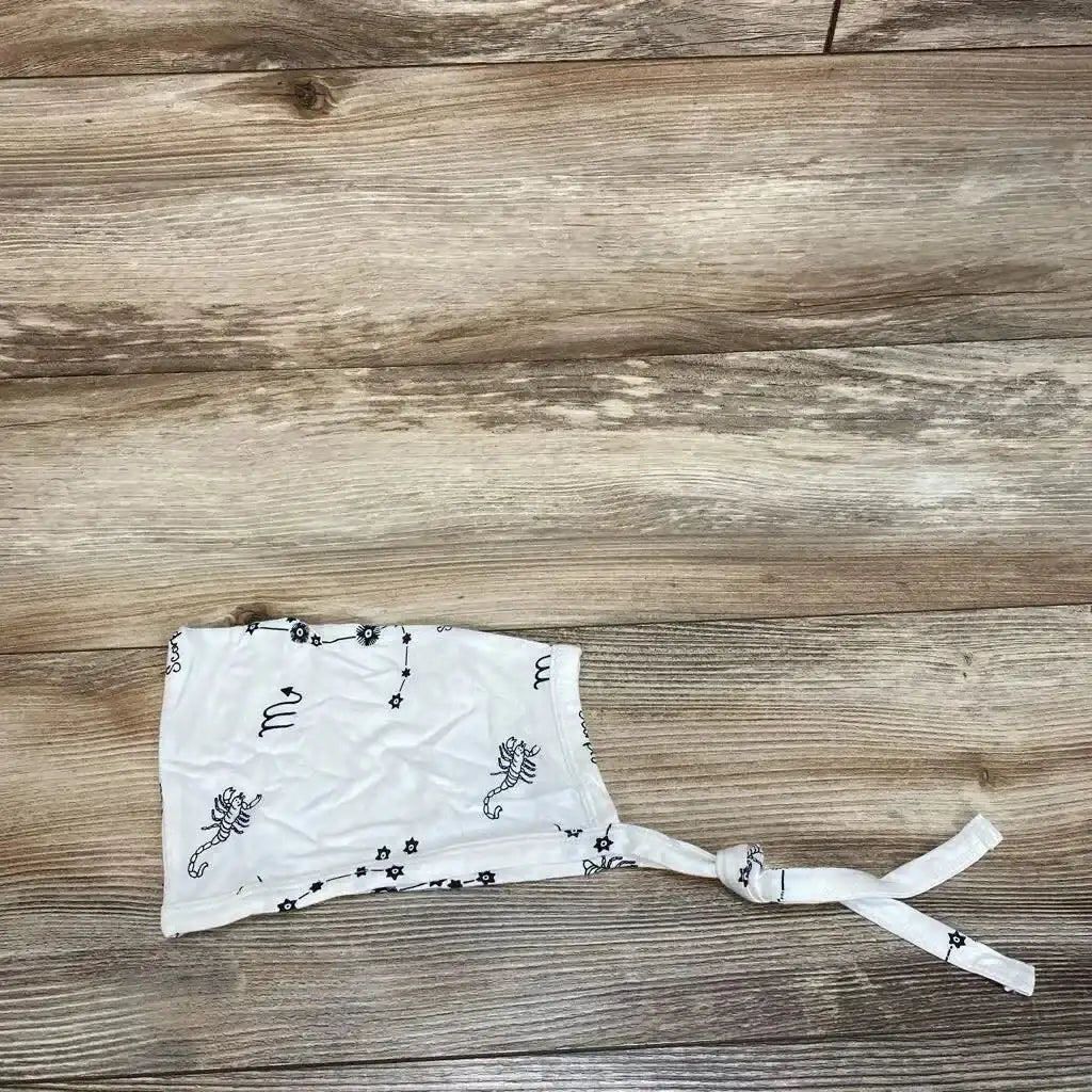 Flat lay of Kate Quinn Scorpio elf hat showcasing white cotton bonnet with scorpion and floral print and tie back on wood floor