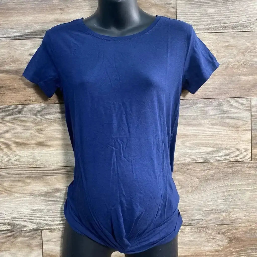 Front view of navy Gap maternity twist-knot tee showing knotted hem and short sleeves on black torso with wood background