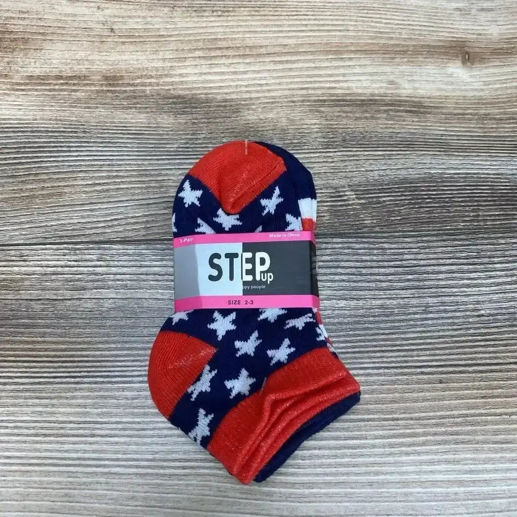 Top-down view of navy baby socks with white stars and red toes, STEP up label size 2-3 on light wood background