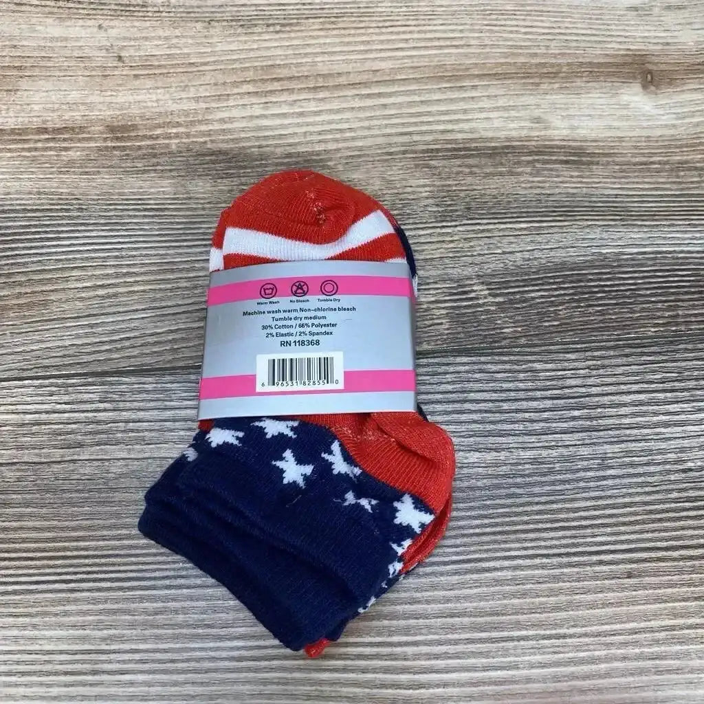 Top-down view of 3-pack toddler ankle socks showing red, white, and navy star-and-stripe patterns with retail band on wood background