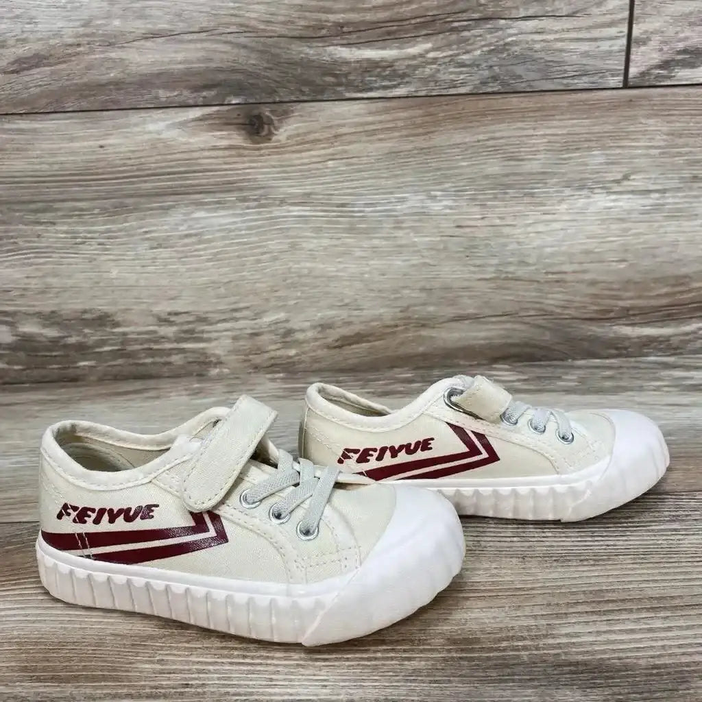 Side view of Feiyue Fe Lo 1920 toddler canvas sneaker, tan with maroon stripe, hook-and-loop strap and white rubber toe on wood-grain background