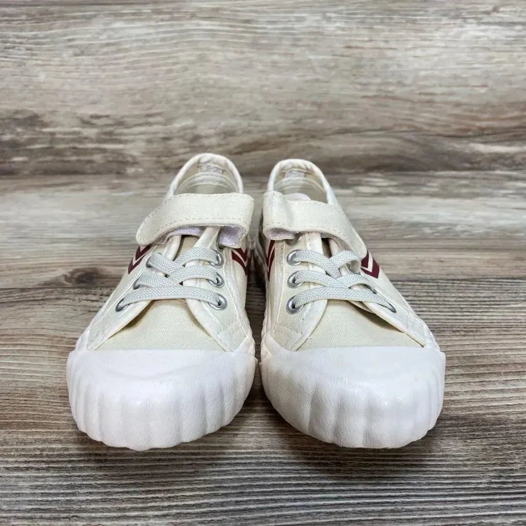 Front view of tan Feiyue Fe Lo toddler sneaker size 7.5C showing velcro strap, red chevron and ribbed white toe on wood