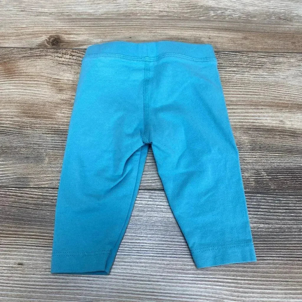 Flat lay of aqua baby leggings (0-3M) showcasing full-length straight legs and elastic waistband on wooden floor background