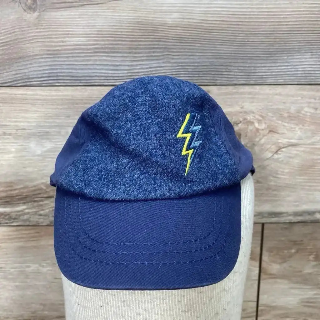 Front view of blue toddler baseball cap showcasing embroidered yellow and teal lightning bolt on wood plank background