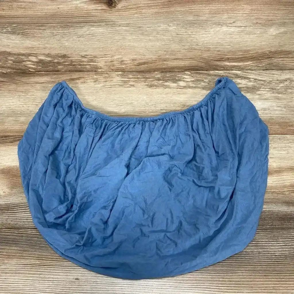 Top-down view of blue Birdie Bean changing pad cover showing elastic edge and wrinkled cotton fabric on wood background