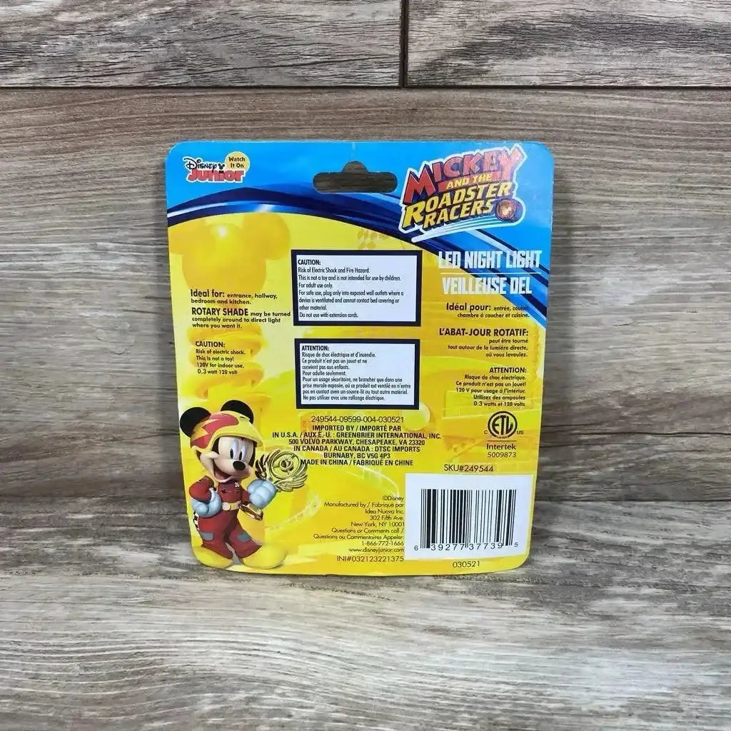 Rear view of Disney Mickey Mouse LED night light packaging showing warnings and barcode with wooden floor background
