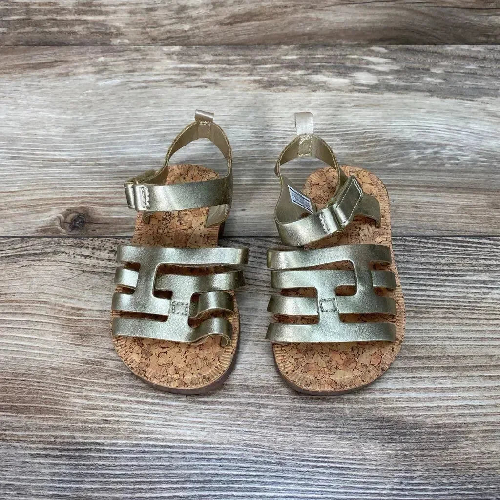 Top view of OshKosh Raquel toddler sandals size 5C showcasing metallic gold straps and cork footbed on wooden background