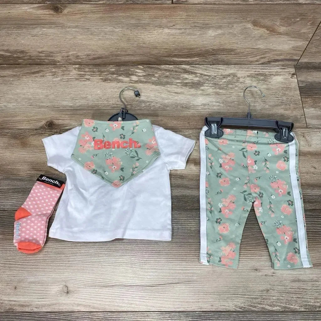Flat lay of Bench 4-piece baby outfit 0-3m: white tee with floral bib, mint floral leggings with white stripes, pink socks