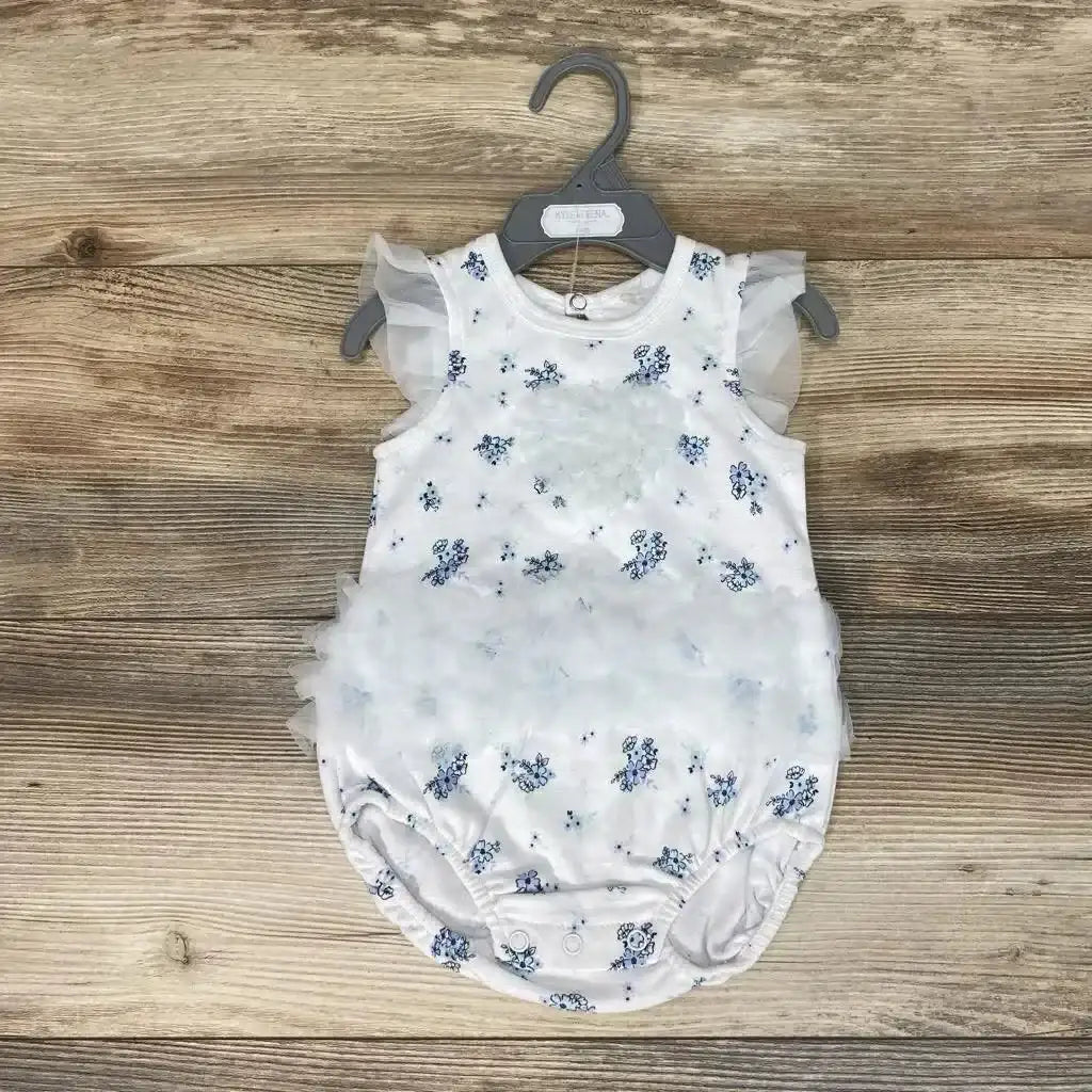 Front view of white floral baby romper with tulle ruffle sleeves and layered ruffle front, snaps at crotch on wood background