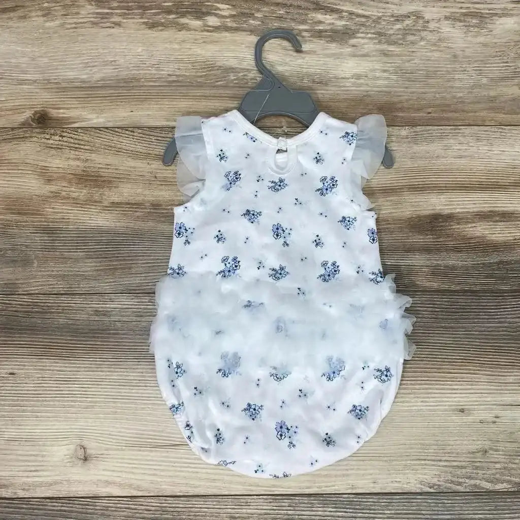 Top view of white floral ruffle romper (3–6M) showcasing organza flutter sleeves and layered ruffle skirt on wood background