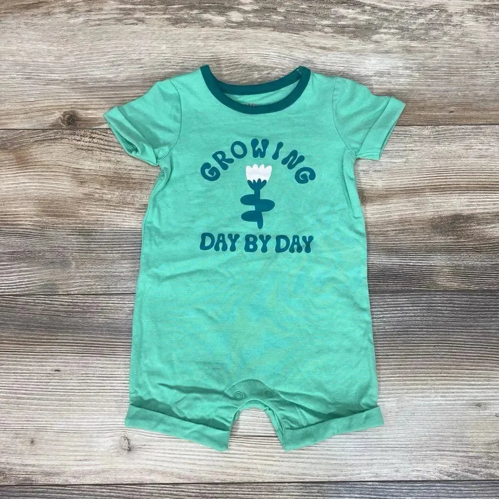Flat lay of Cat & Jack green romper with teal collar, flower graphic reading 'Growing Day by Day', and snap crotch on wood background