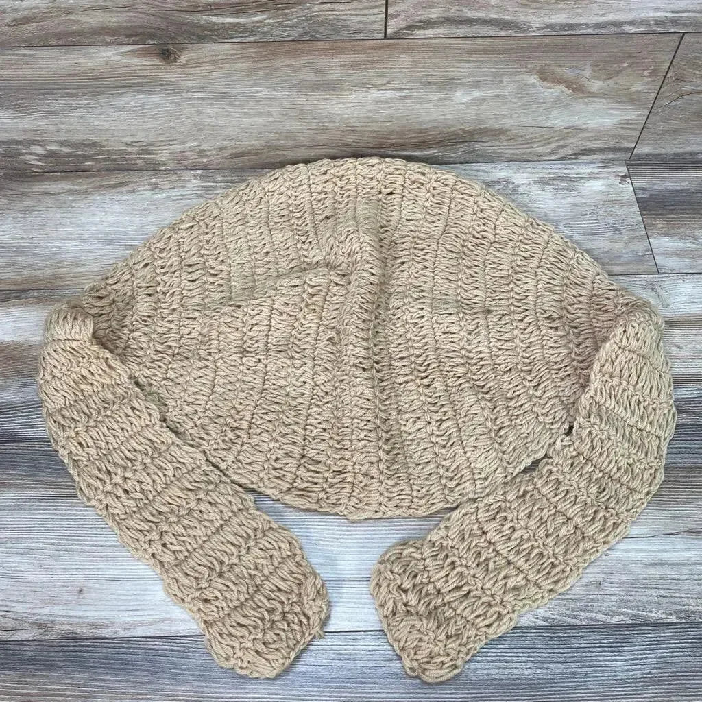 Top-down view of beige hand-knitted newborn hammock showing chunky ribbed crochet texture and straps on wood