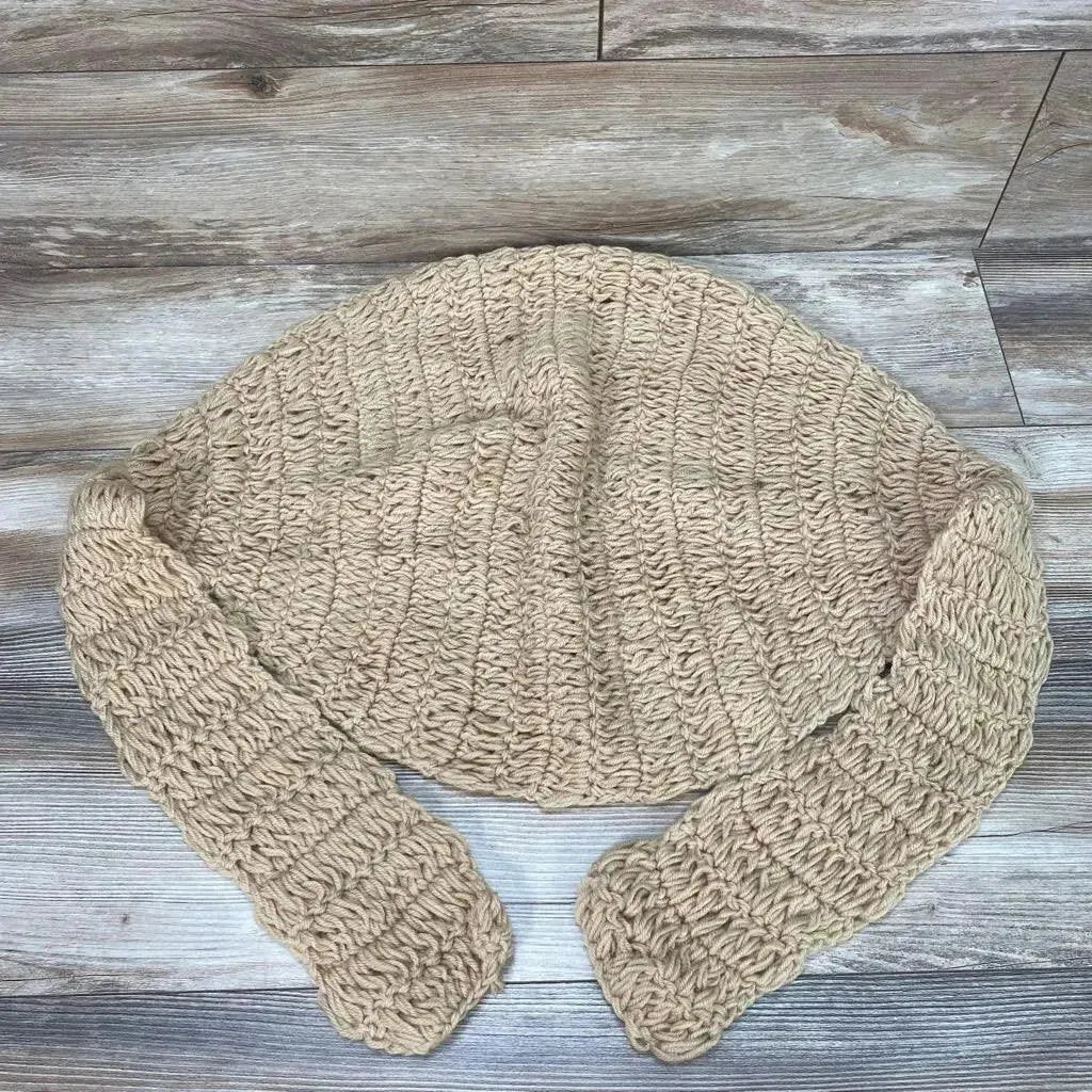 Top-down view of beige hand-knitted newborn hammock showing chunky ribbed crochet texture and straps on wood