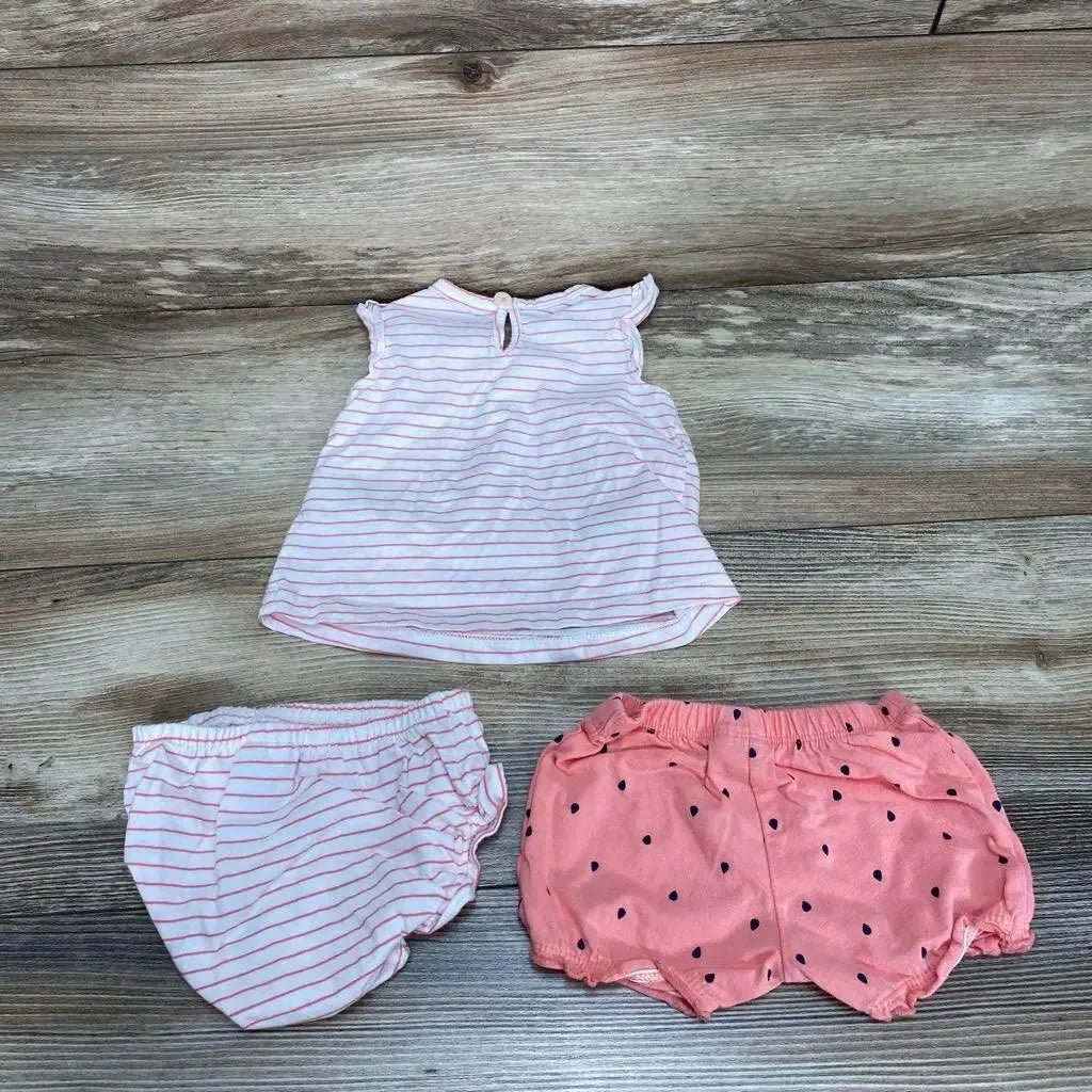 Flat lay of 3-piece 3M baby outfit: pink striped top with keyhole, striped bloomers, and coral dotted shorts on wood
