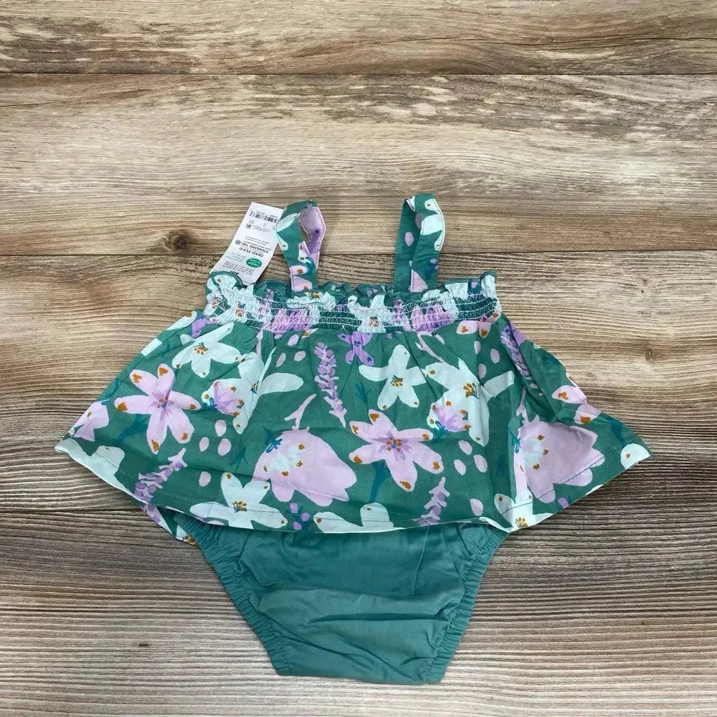 Top view of green floral baby bodysuit dress (3M) with smocked bodice, ruffle skirt and attached diaper cover on wood