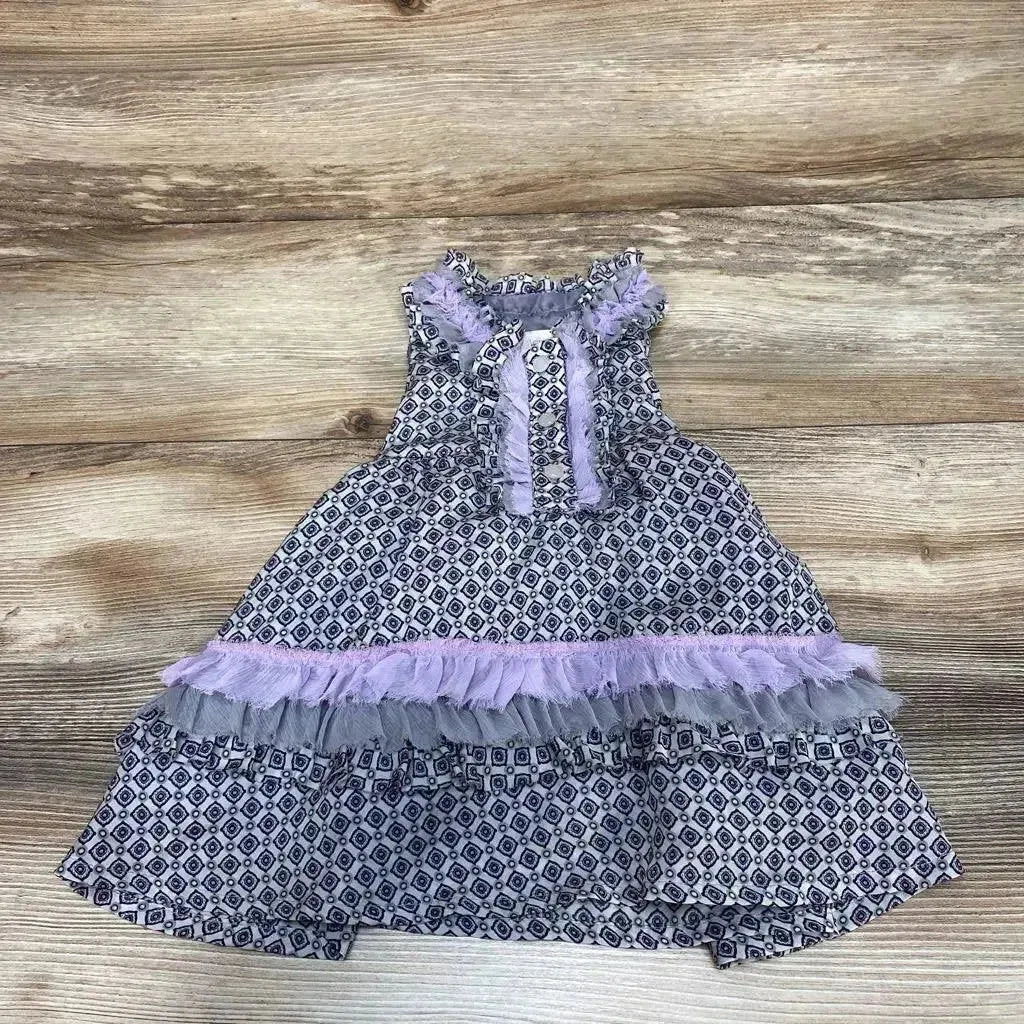 Top-down view of grey 6-month ruffle dress with navy geometric print and lilac tulle trim, sleeveless, flat-lay on wood background
