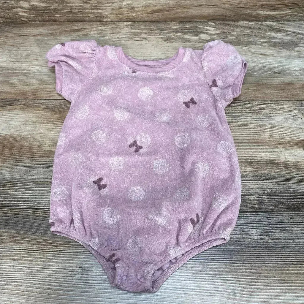 Top-down view of purple Minnie Mouse terry baby romper with puff sleeves, polka dot and bow print, elastic leg openings and snap crotch on wood background