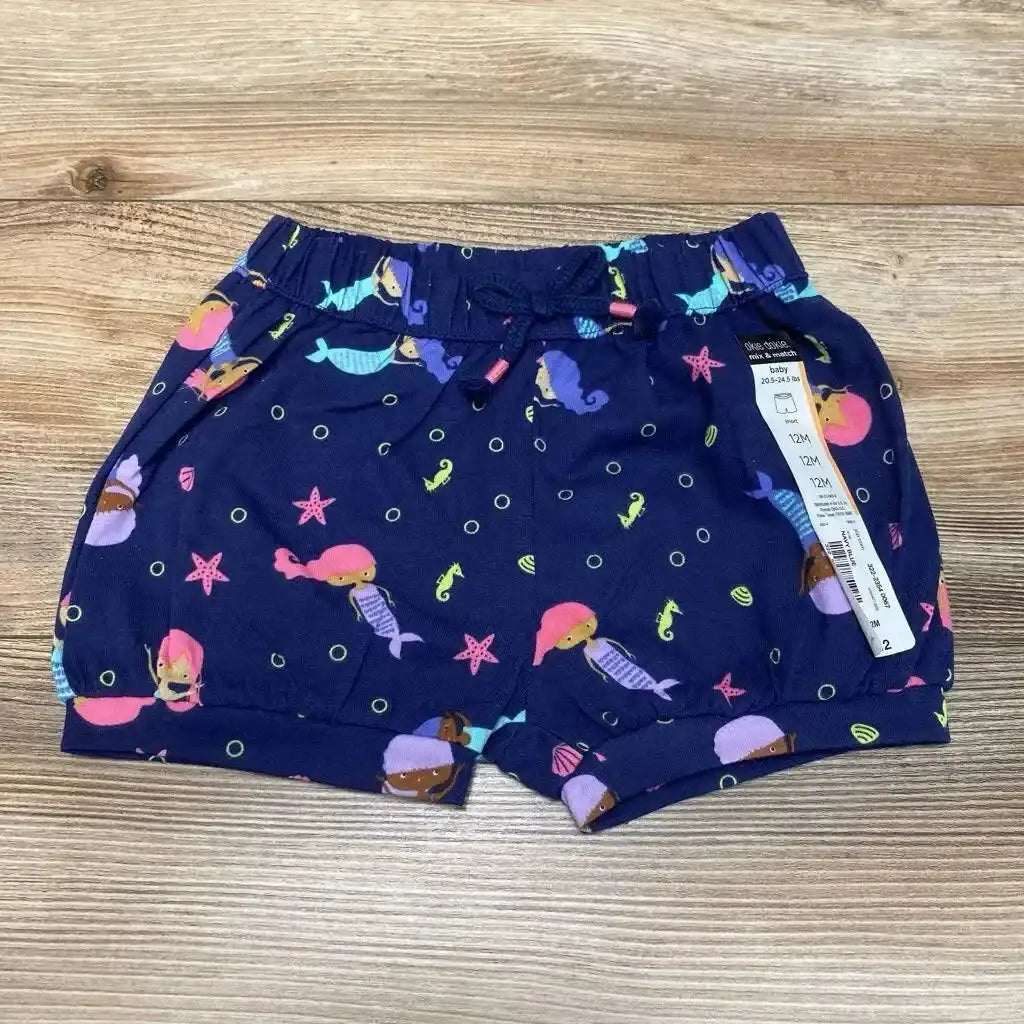 Top-down view of navy baby bubble shorts (12M) with colorful mermaid print, elastic drawstring waist and cuffed legs on wood