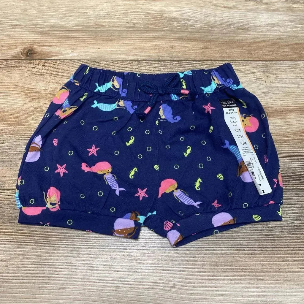 Top-down view of navy baby bubble shorts (12M) with colorful mermaid print, elastic drawstring waist and cuffed legs on wood