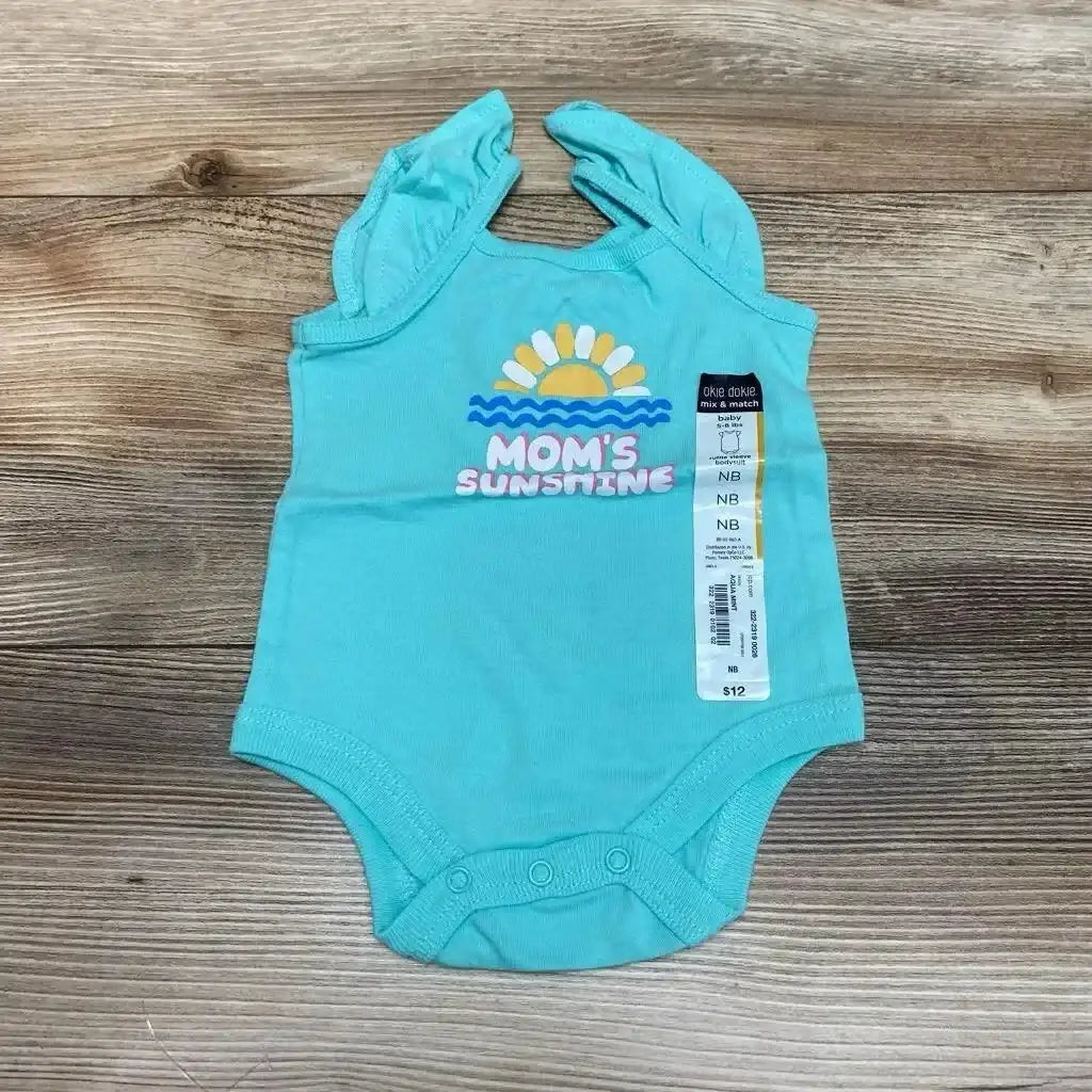 Flat lay of NEW Okie Dokie Tank Bodysuit Mom’s Sunshine size Newborn showcasing teal ruffle-strap bodysuit with sunshine graphic and hangtag on wood plank surface