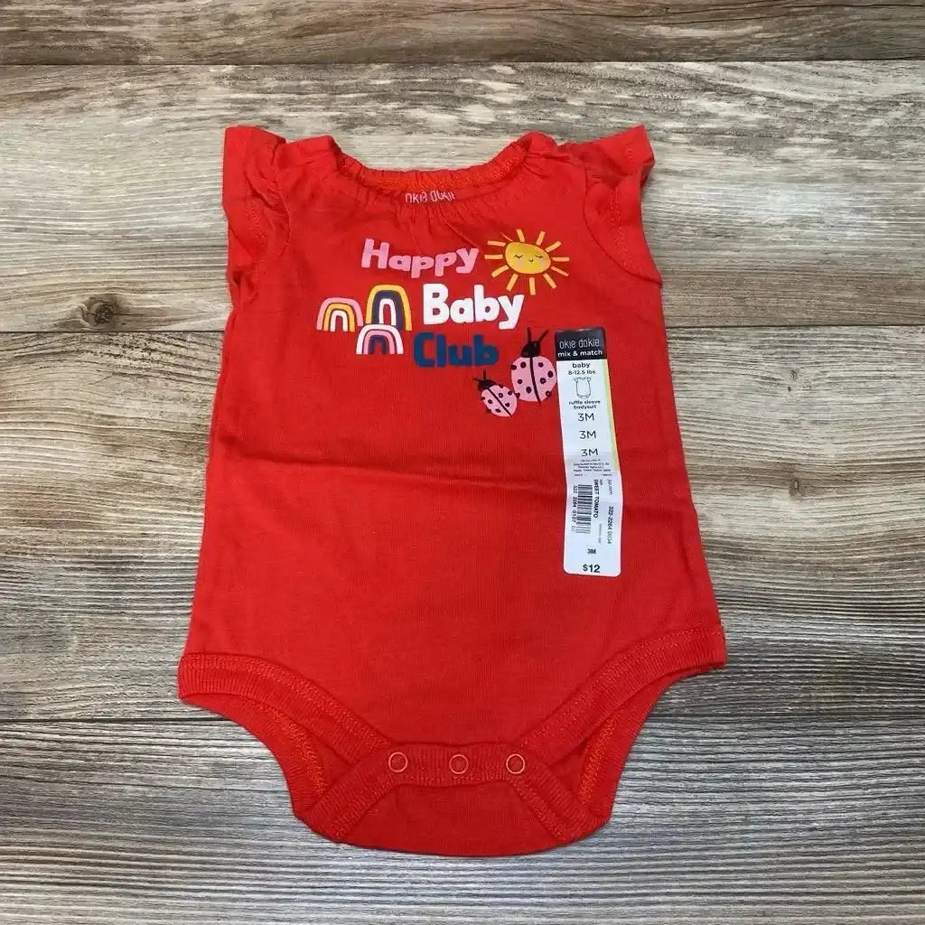 Flat lay of red Okie Dokie 3M baby bodysuit showing 'Happy Baby Club' print, ruffled sleeves and price tag on wood