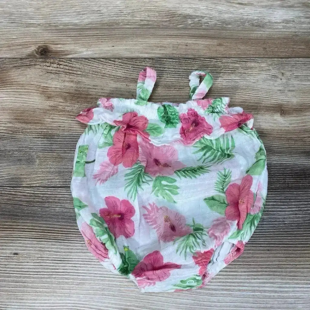Flat lay of white baby bubble romper (size 0-3M) showcasing pink hibiscus print and ruffle trim on wood background