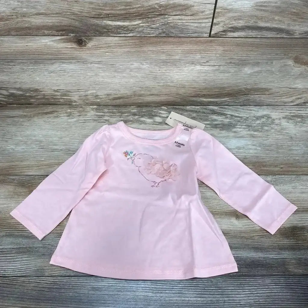 Flat lay of pink First Impressions birdie shirt (6-9m) showing fabric flower applique on chest on wood background