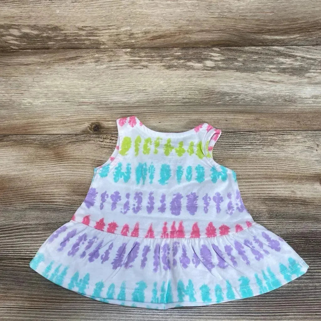 Front view of white 3M tie-dye baby tank top with pastel rainbow stripes and ruffle hem on wood background
