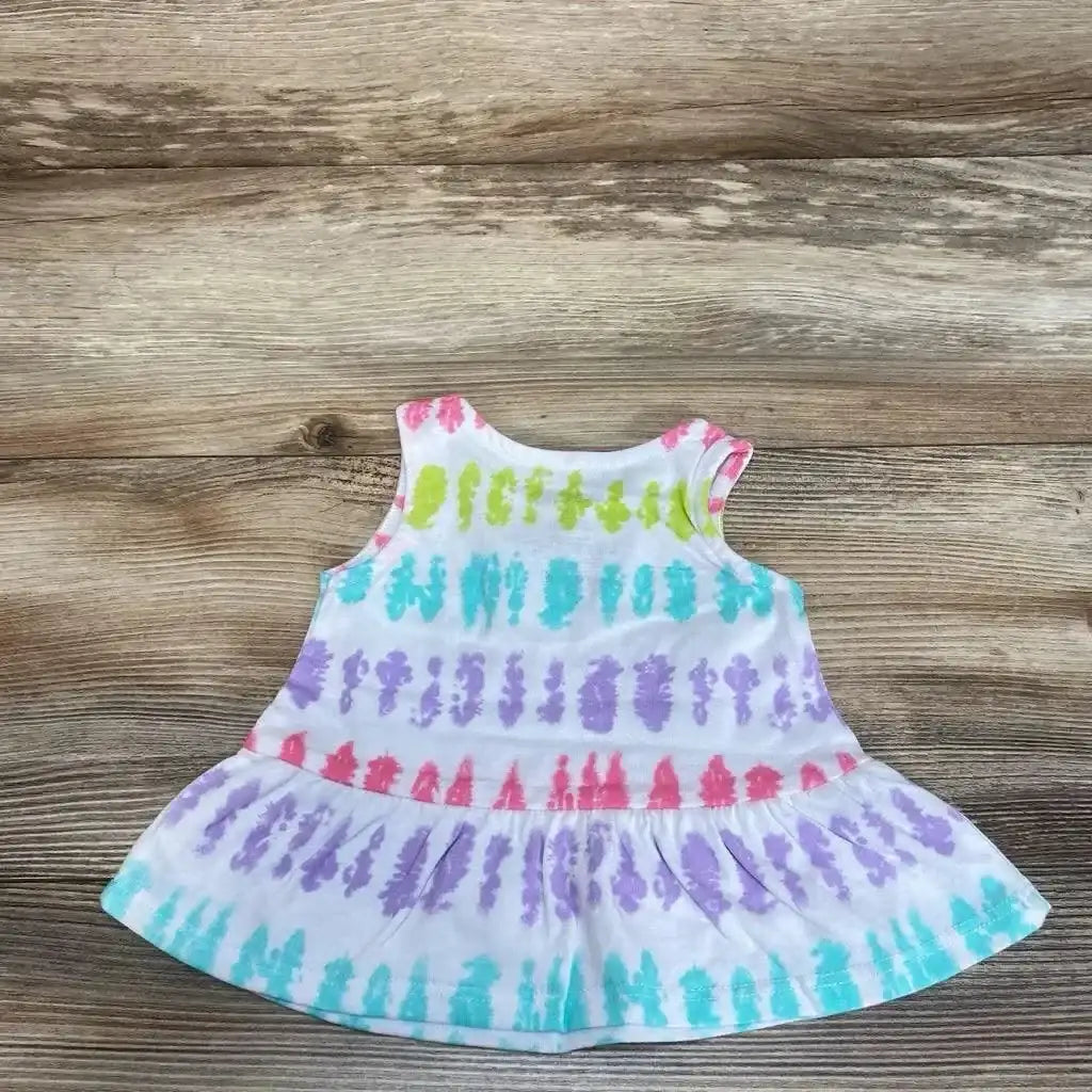 Front view of white 3M tie-dye baby tank top with pastel rainbow stripes and ruffle hem on wood background