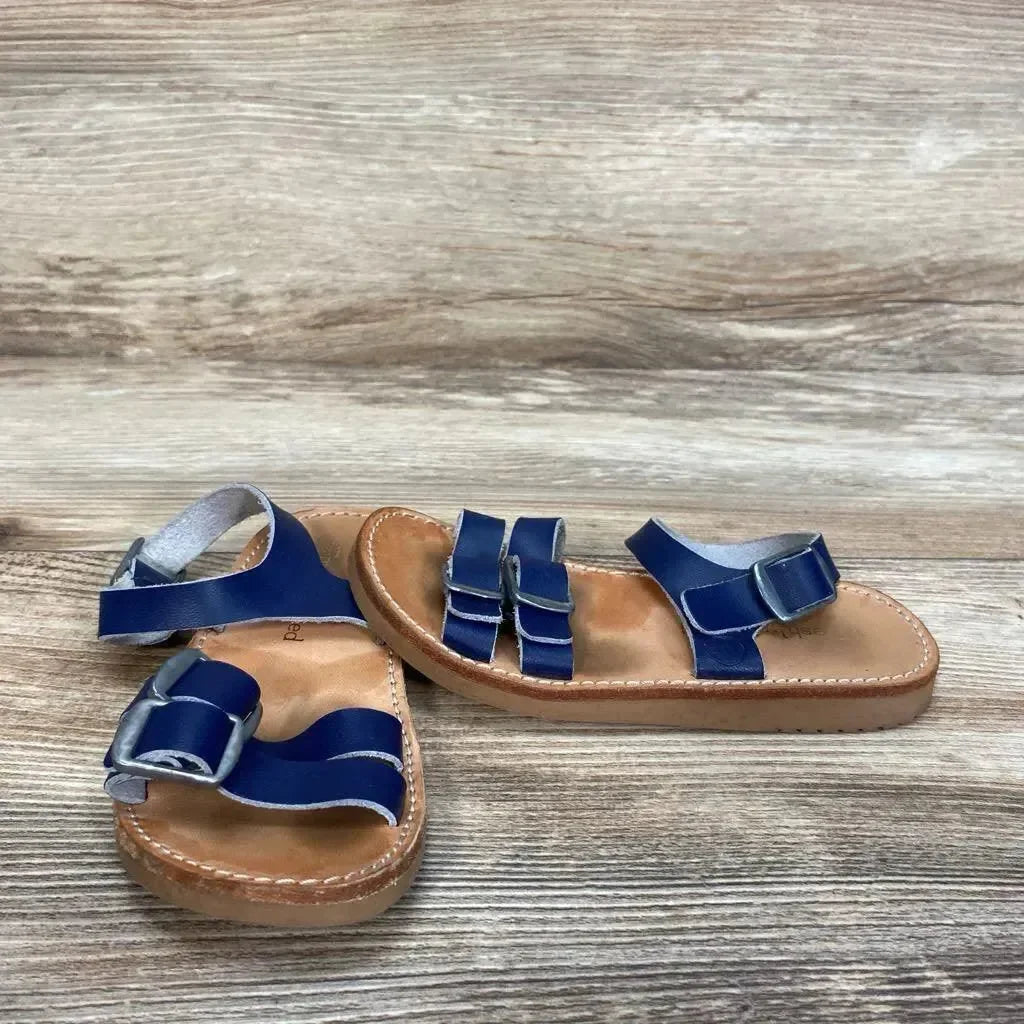Angled overhead of navy Freshly Picked Rockaway sandals with double front straps, ankle buckle and tan stitched sole on wood