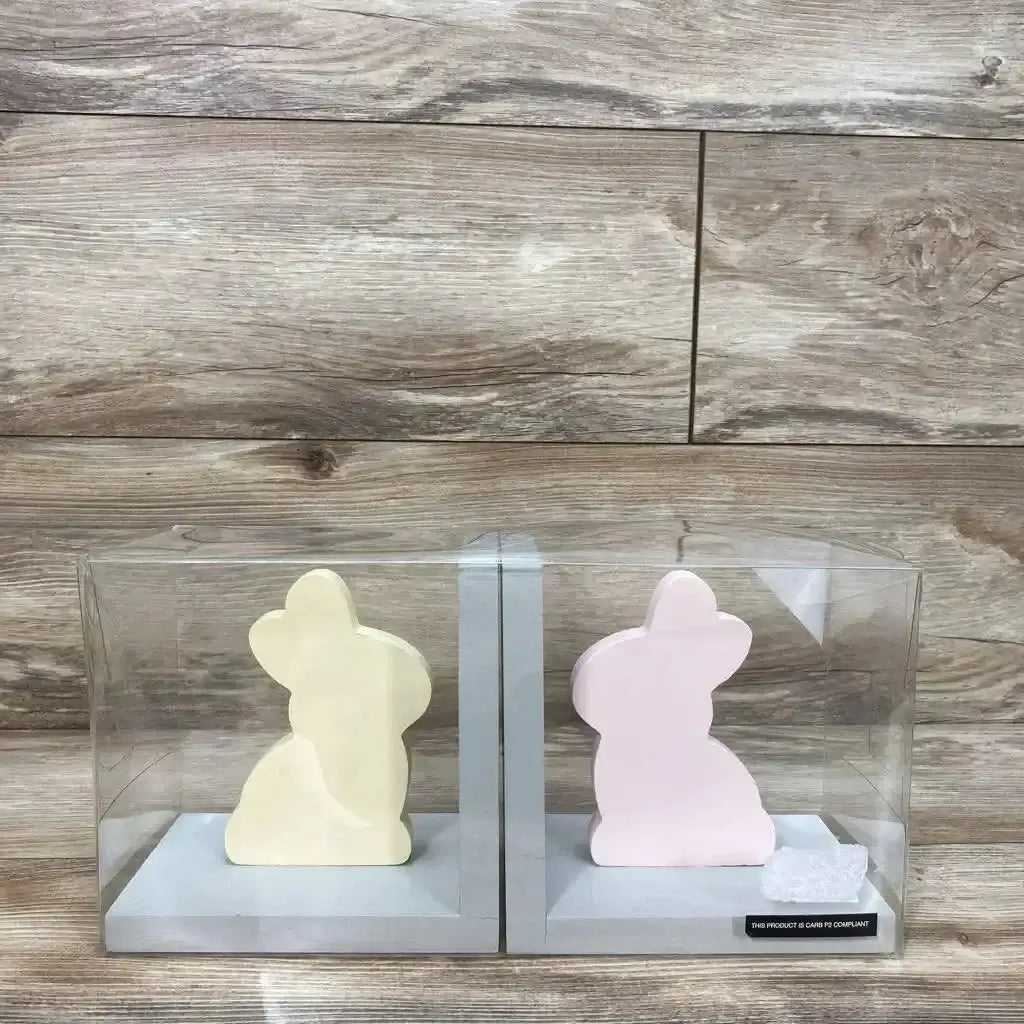 Front view of New Concepts kids pair bookends with yellow and pink bunny shapes, in clear display boxes on wood background