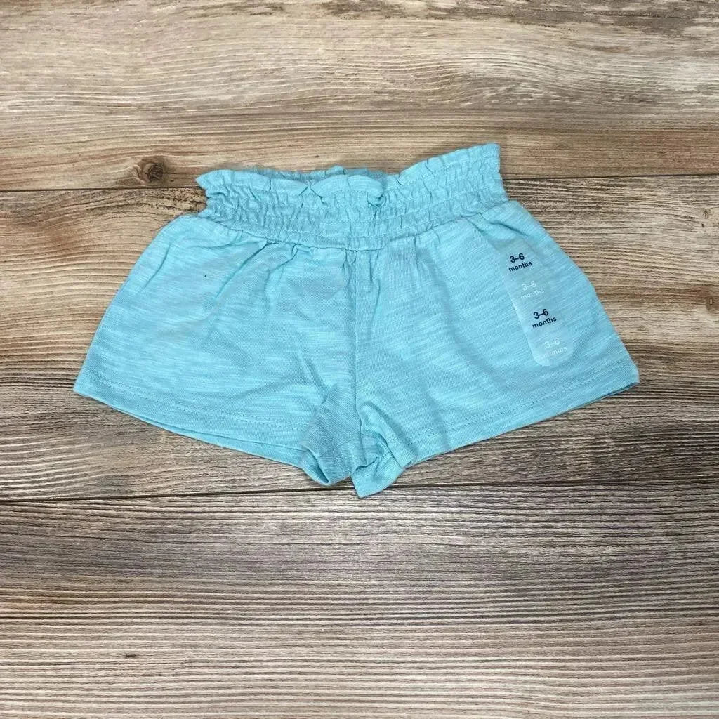 Flat lay of aqua Baby Gap pull-on shorts (3–6 months) showcasing ruffled elastic waist and soft knit on wood background