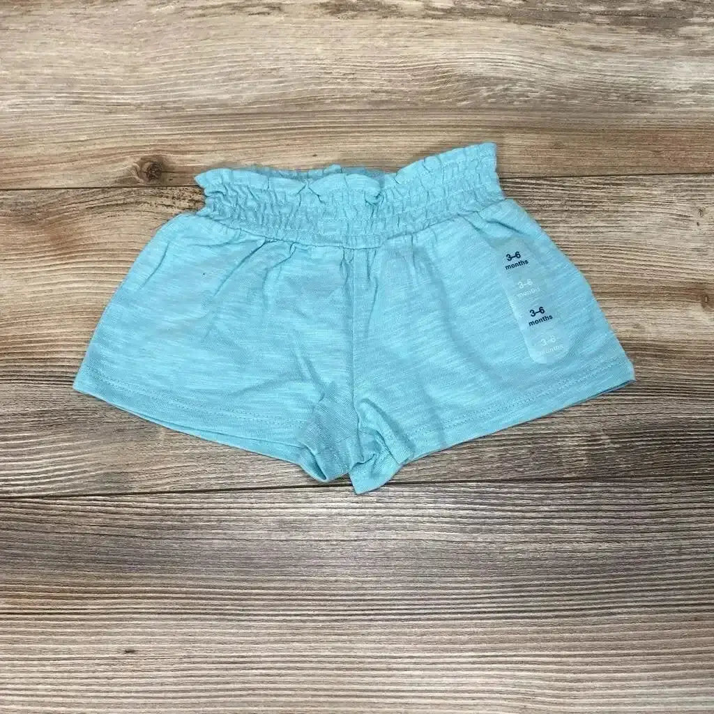 Flat lay of aqua Baby Gap pull-on shorts (3–6 months) showcasing ruffled elastic waist and soft knit on wood background