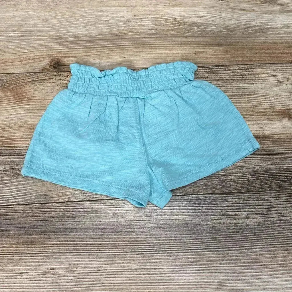Flat lay of aqua Baby Gap pull-on shorts showing ruffled elastic waist and soft knit fabric on wood background