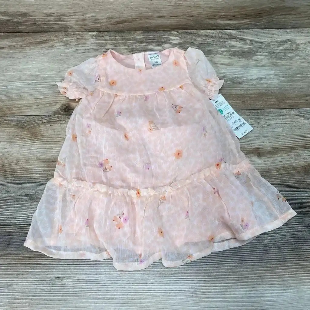 Flat lay of pink floral baby dress with matching bloomers showing puff sleeves and ruffled hem on light wood background
