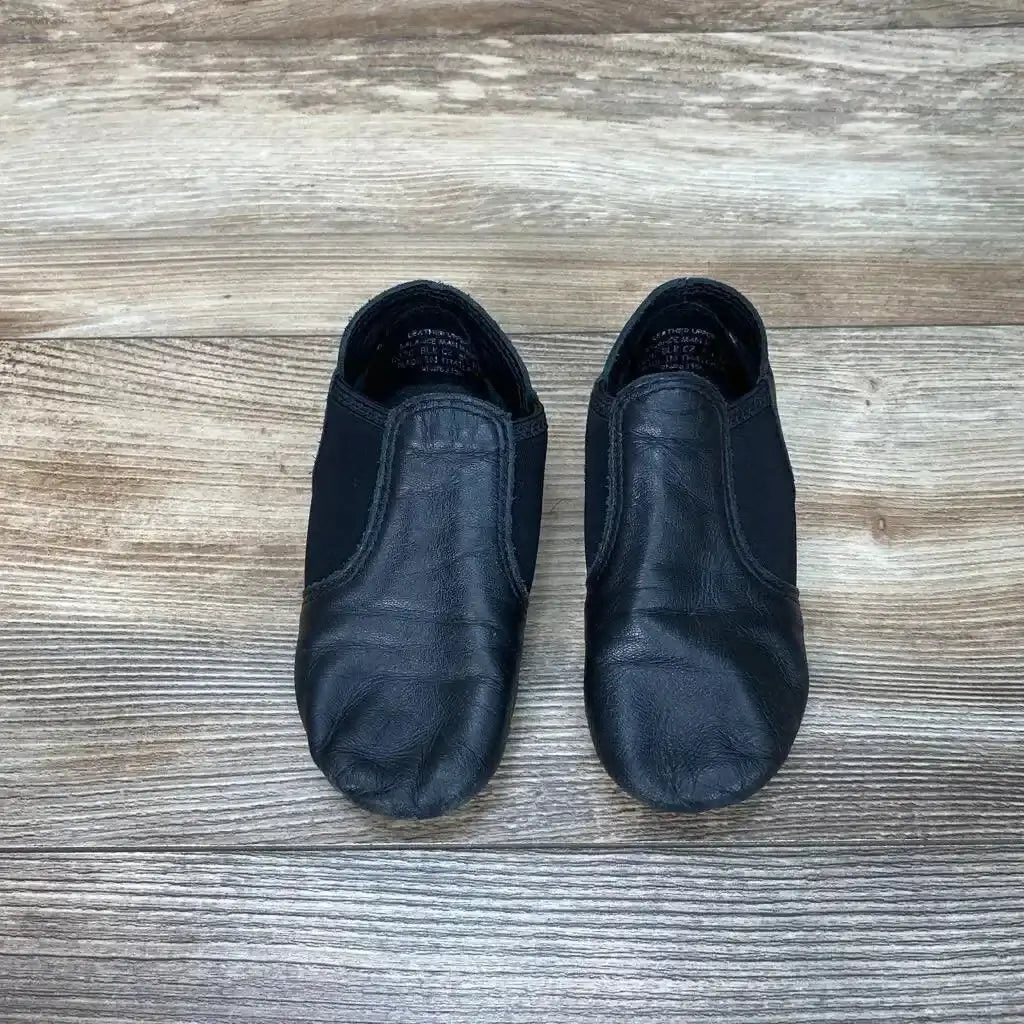 Three-quarter side view of black Capezio E-Series jazz slip-on shoes size 11C showcasing elastic gore and split sole on white background