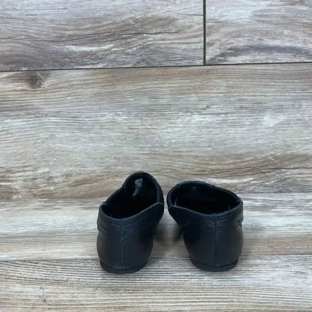 Back view of Capezio E-Series jazz slip-on shoes in black leather on wood plank floor