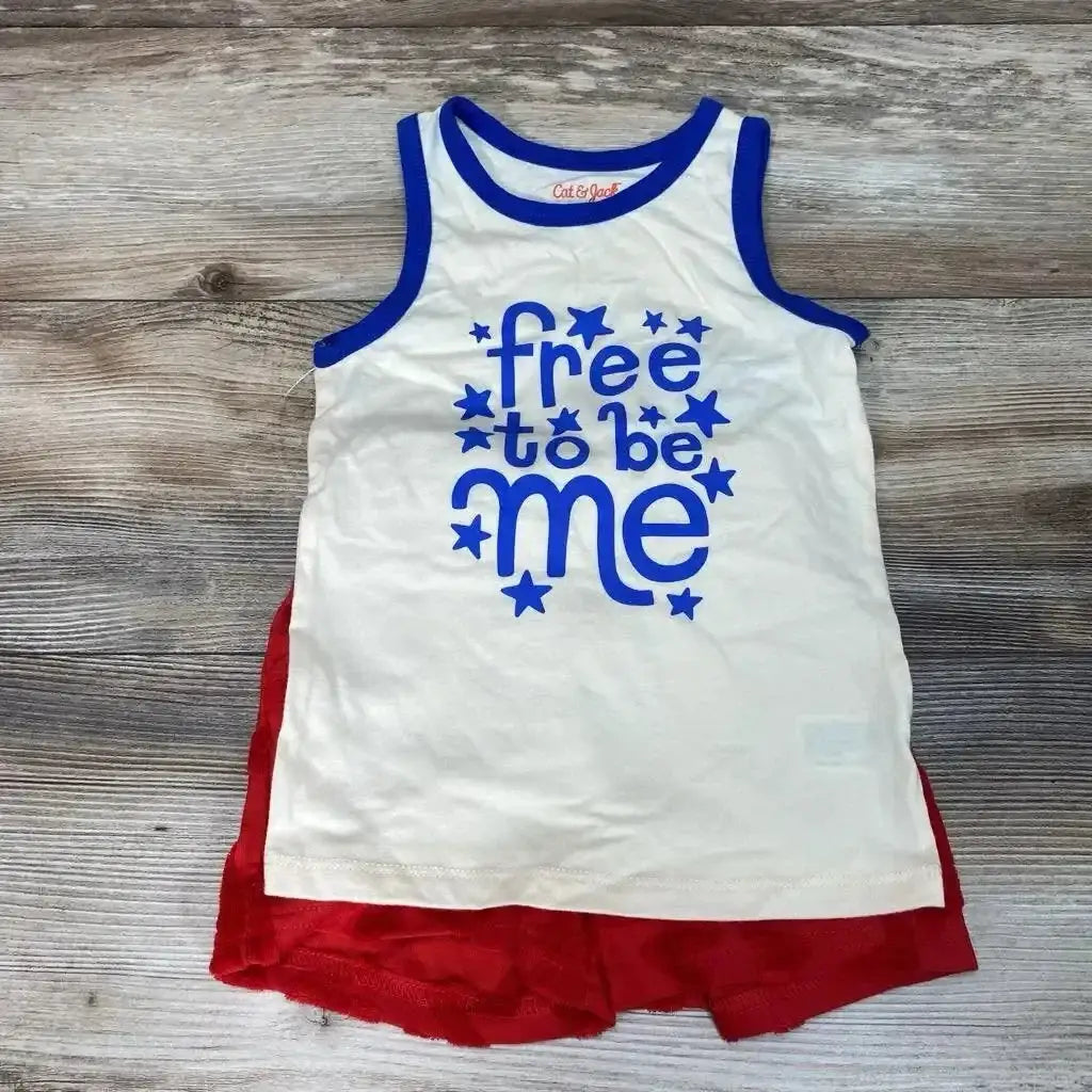 Flat lay of new Cat and Jack two-piece set with white Free To Be Me star graphic tank and red ruffle shorts on wood plank floor