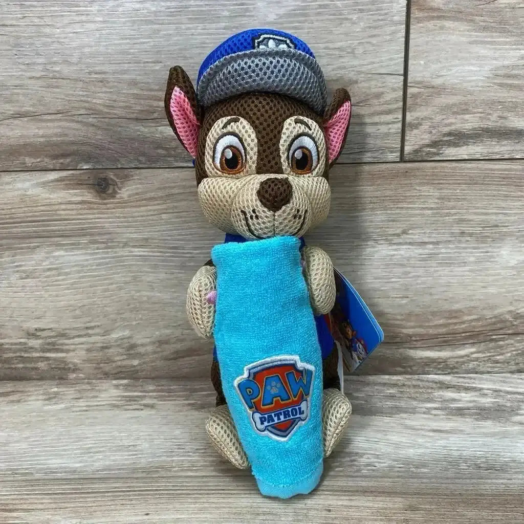 Front view of Paw Patrol bath towel and washcloth set with Chase plush holding a blue towel with PAW logo on wood background