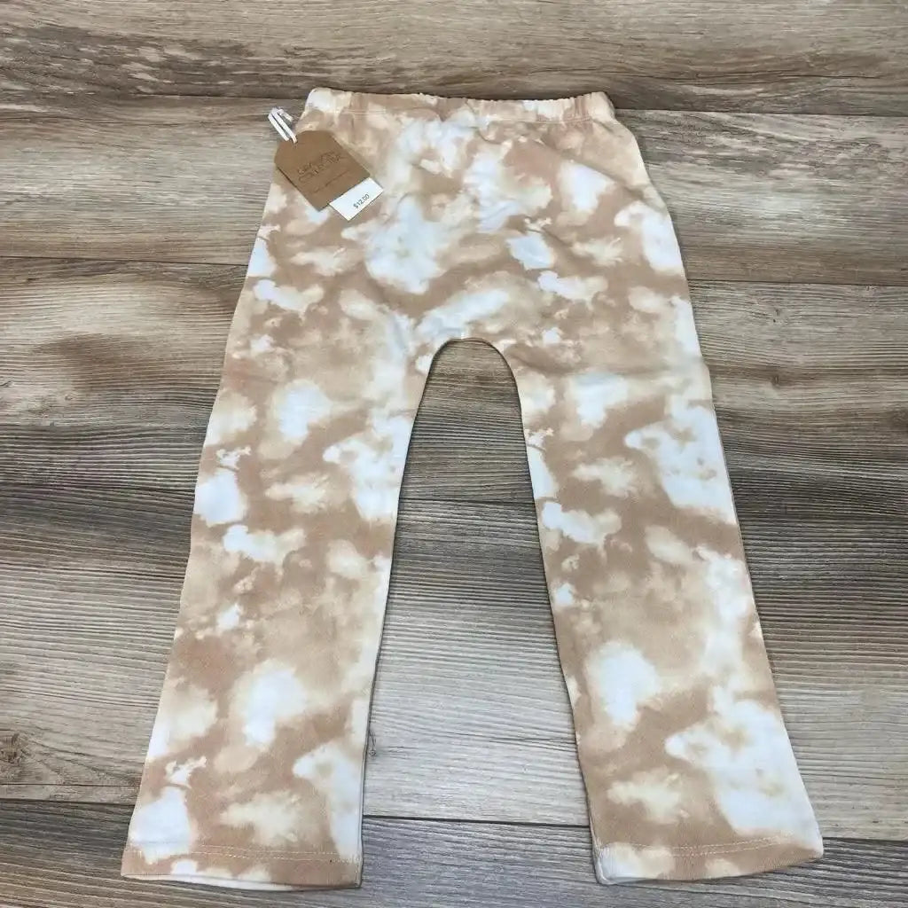 Flat lay of Grayson Collective tie-dye toddler pants in brown and white, size 4T showing elastic waistband and straight legs on wood floor background