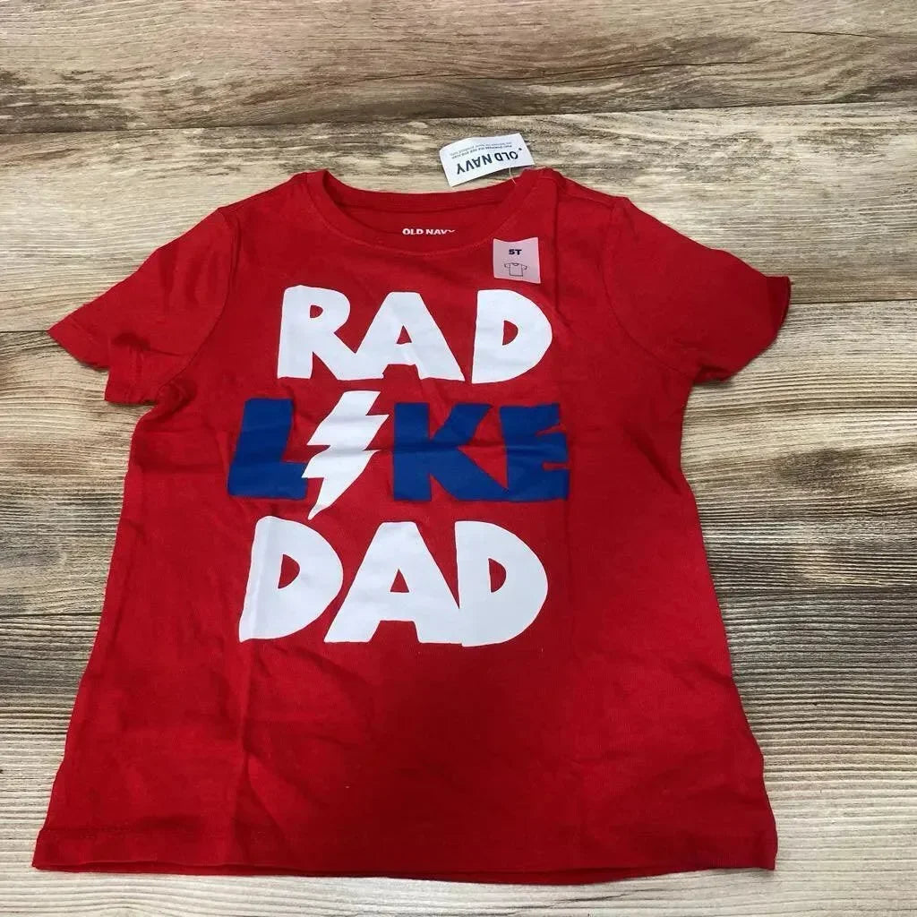 Front flat lay of red Old Navy toddler t-shirt with RAD LIKE DAD graphic and lightning bolt on wood background, 5T tag visible