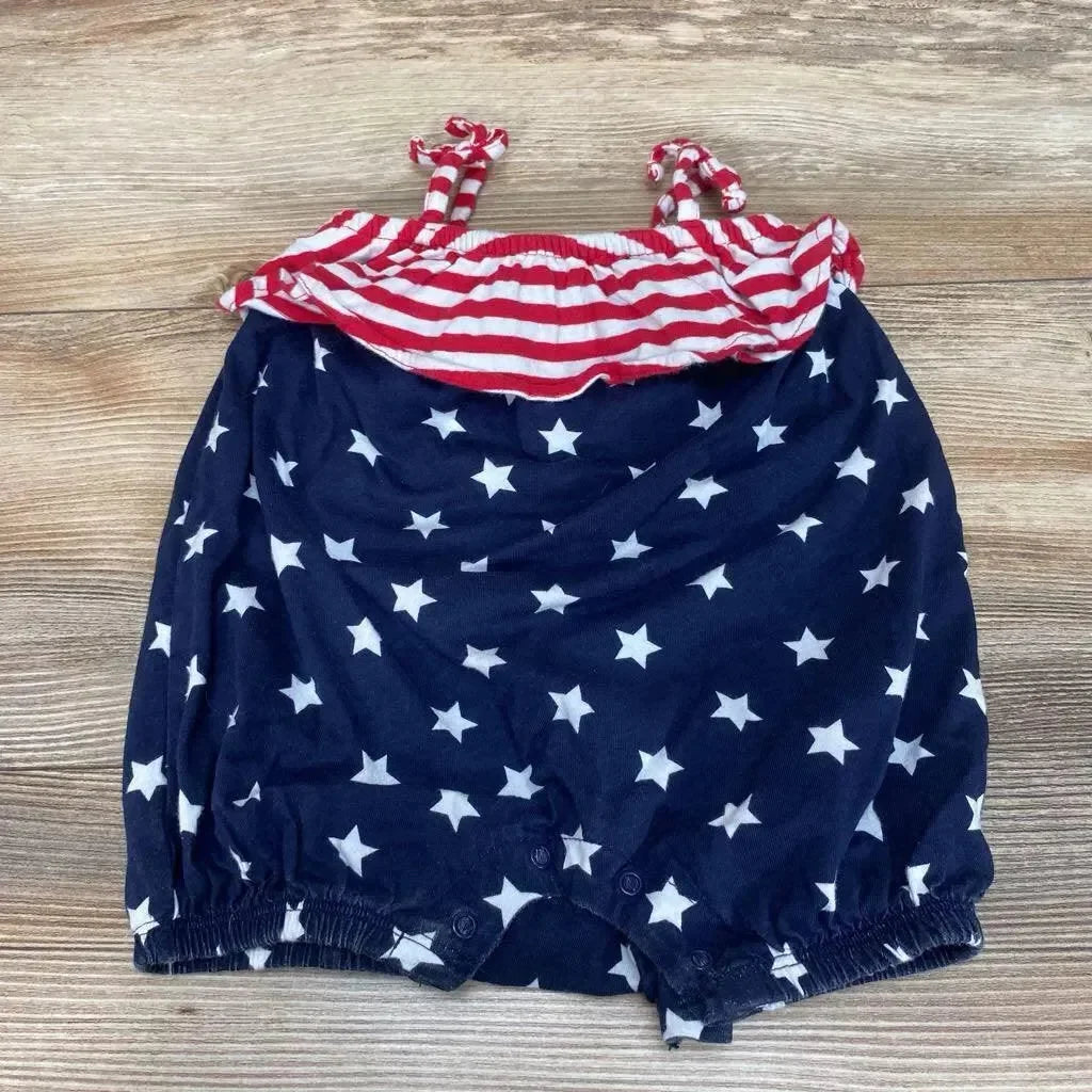 Flat lay of baby shortie romper showing navy star print bottom and red-and-white striped ruffle top with tie straps on wood