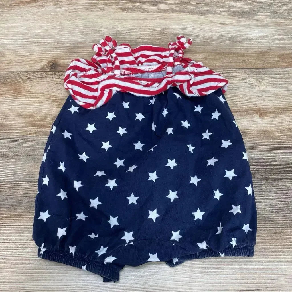 Flat lay of sleeveless 3-6 month romper with red and white striped ruffled top and navy star-print bottom on wood floor