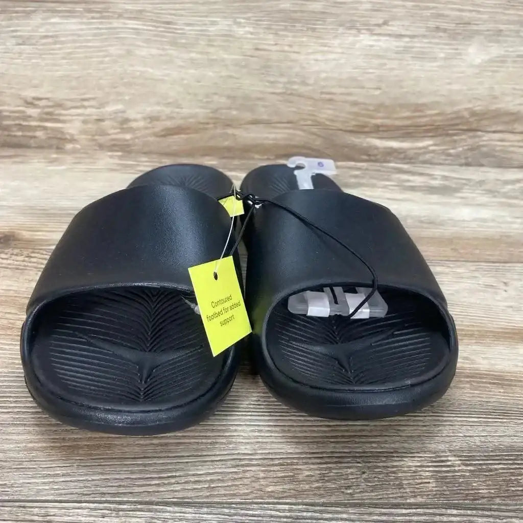 Three-quarter view of All in Motion Apollo Slip-On Slide Sandals sz 6Y showcasing black contoured footbeds with yellow hangtag on wood plank background